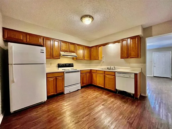 a kitchen with granite countertop a refrigerator stove top oven and cabinets
