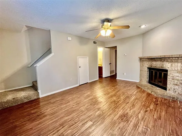 a view of empty room with wooden floor and fireplace