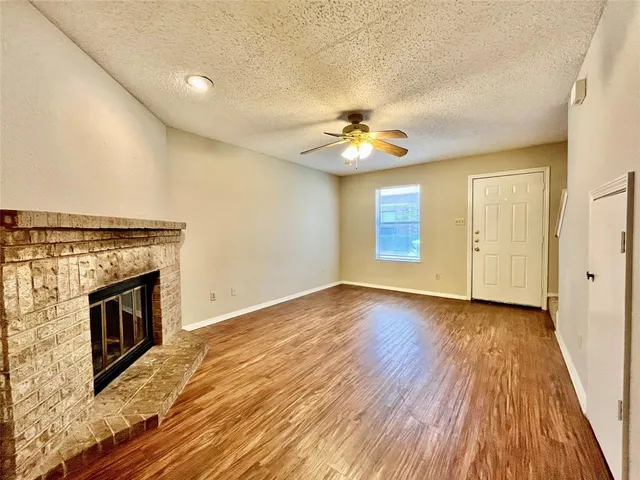a view of an empty room with a fireplace and wooden floor