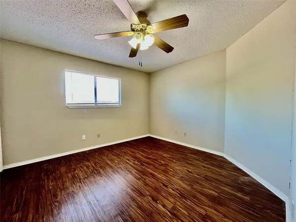 an empty room with wooden floor and a ceiling fan
