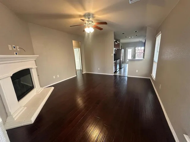 wooden floor in an empty room with a fireplace and a window