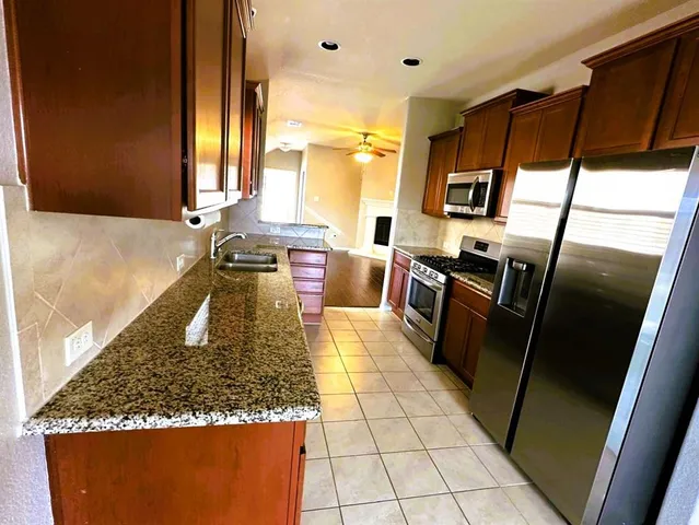 a kitchen with stainless steel appliances granite countertop sink stove refrigerator and cabinets