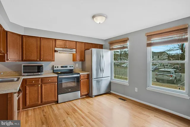 a kitchen with stainless steel appliances granite countertop a stove a sink dishwasher a refrigerator and cabinets with wooden floor