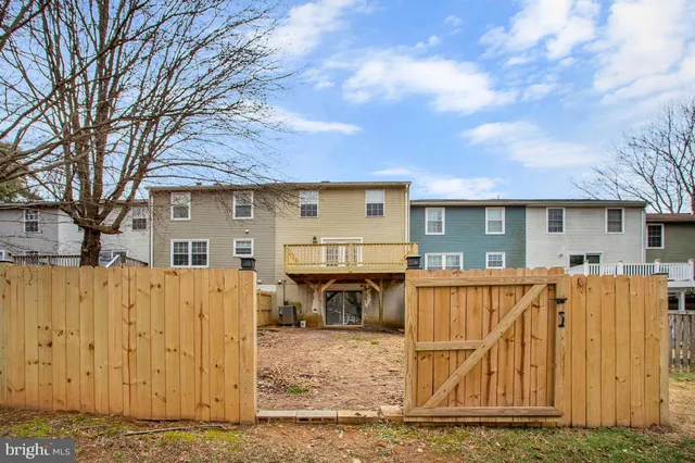 a view of a house with wooden fence next to a yard