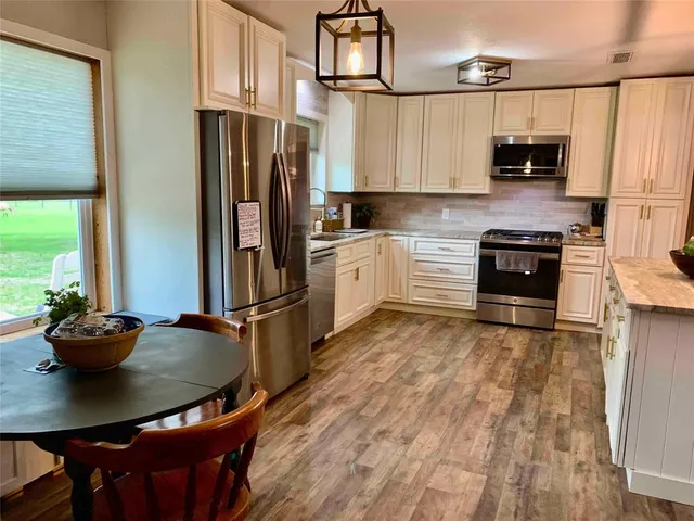 a kitchen with stainless steel appliances granite countertop a refrigerator a stove a sink dishwasher and microwave oven with wooden floor