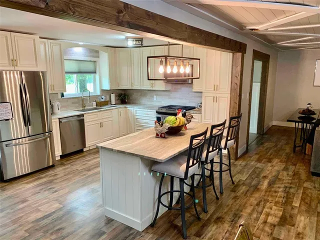 a kitchen with stainless steel appliances granite countertop a kitchen island hardwood floor and a window