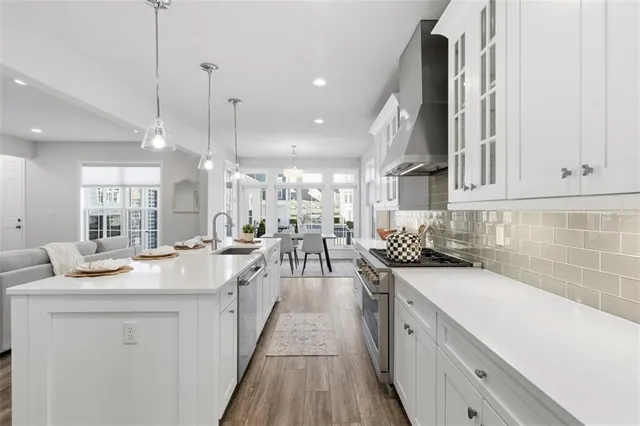 a kitchen with stainless steel appliances granite countertop a sink a stove and a wooden floors