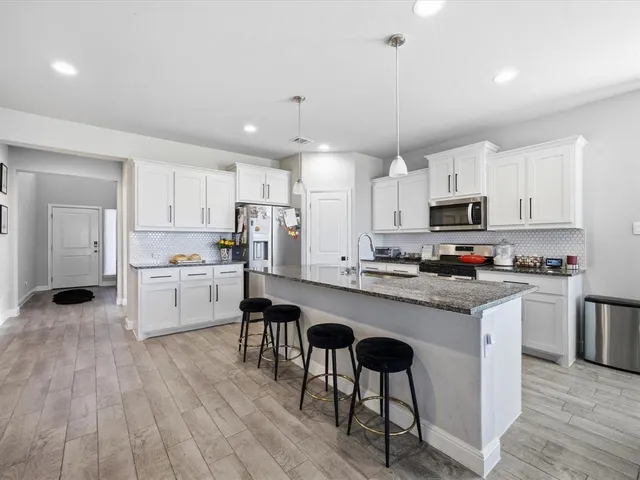 a kitchen with a sink a center island stainless steel appliances and cabinets