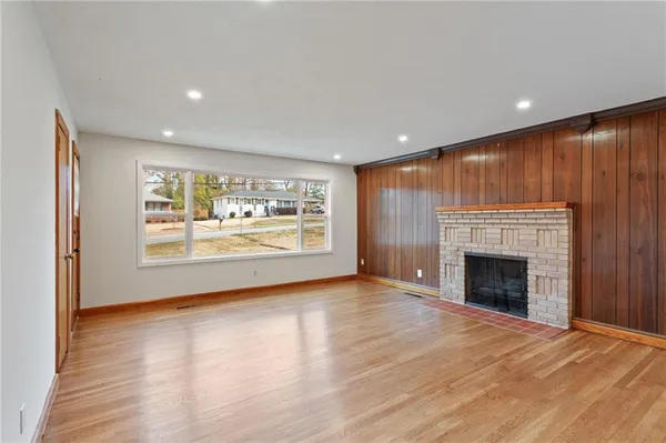an empty room with large windows fireplace and wooden floor