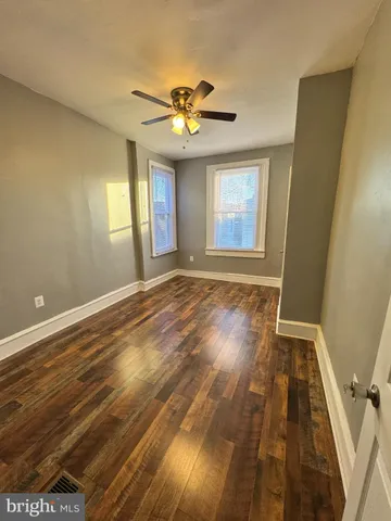a view of an empty room with window and wooden floor