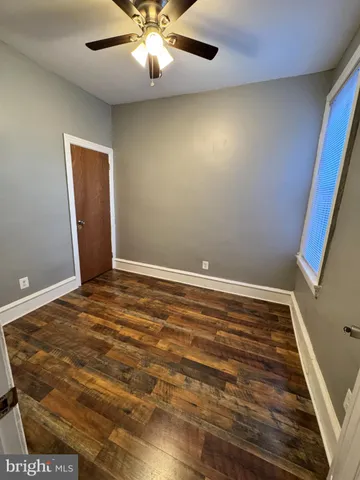 en empty room with wooden floor and fan