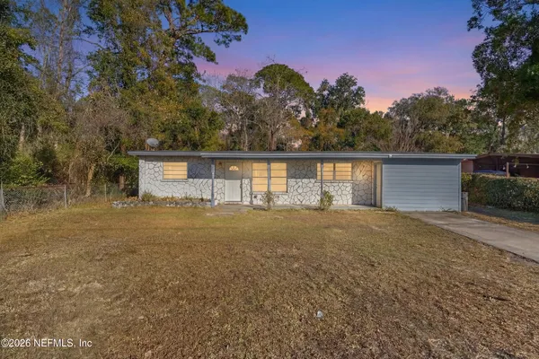 a front view of house with yard and trees in the background