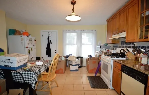 a kitchen with stainless steel appliances a stove a sink a dining table and chairs with wooden floor