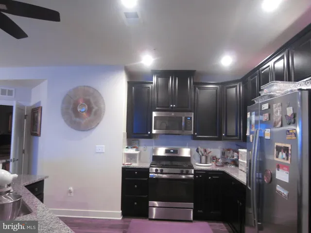 a kitchen with stainless steel appliances granite countertop a refrigerator and a stove top oven
