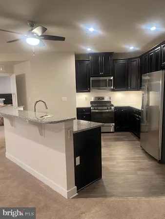 a kitchen with kitchen island granite countertop a sink and a refrigerator