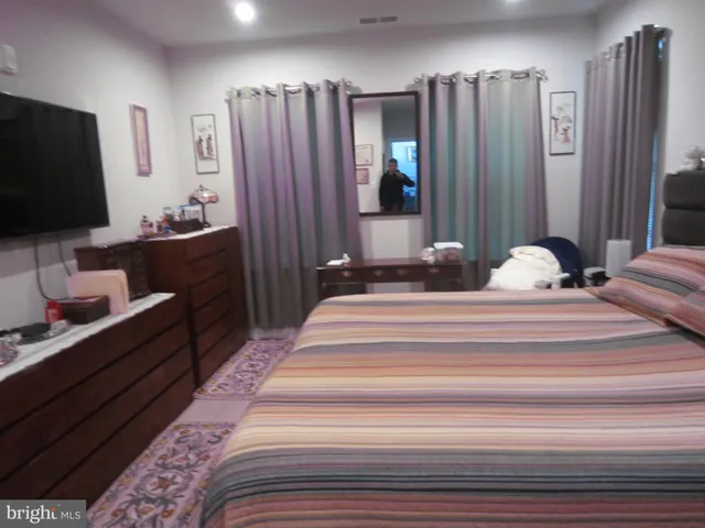 a bedroom with a bed and a flat tv screen on dresser