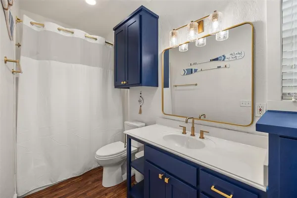 a bathroom with a granite countertop sink toilet a mirror a vanity and shower
