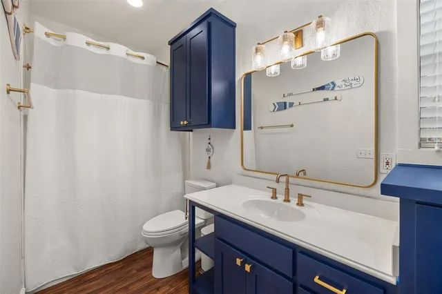 a bathroom with a granite countertop sink toilet a mirror a vanity and shower