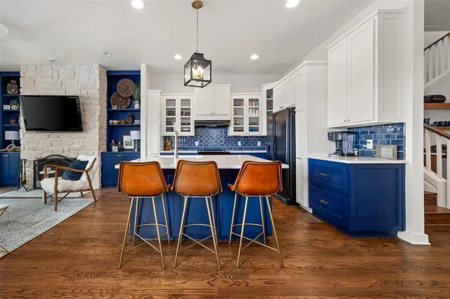 a open kitchen with stainless steel appliances granite countertop a stove a refrigerator a kitchen island a dining table and chairs with wooden floor