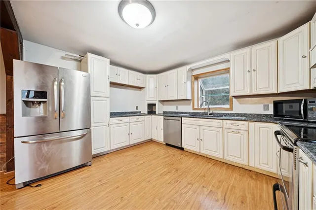 a kitchen with granite countertop a refrigerator stove top oven and sink
