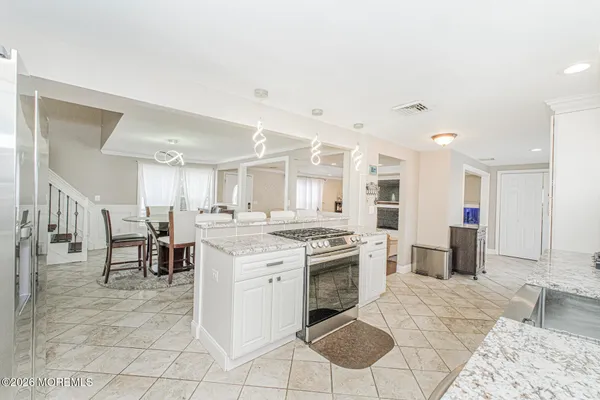 a large kitchen with kitchen island a sink a stove a dining table and chairs