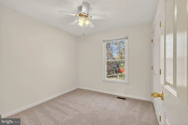 an empty room with a window and a ceiling fan