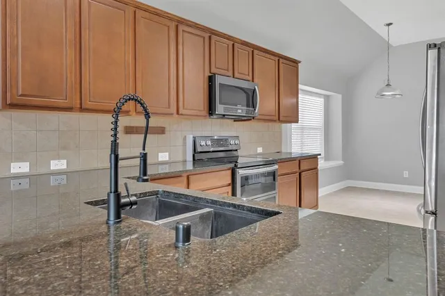 a kitchen with stainless steel appliances granite countertop a sink a stove and a microwave