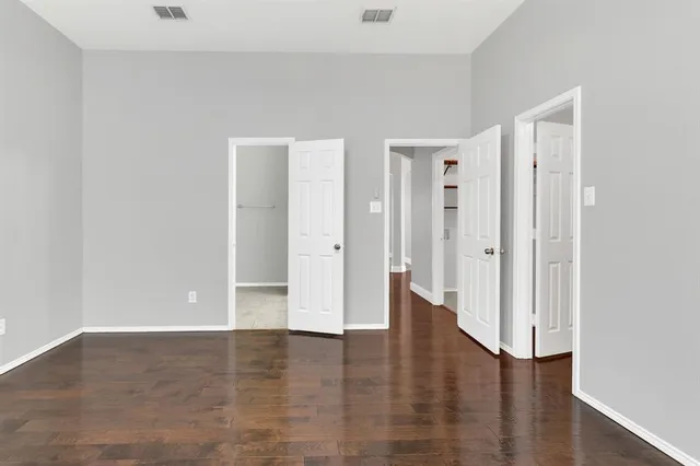 a view of an empty room with wooden floor and closet