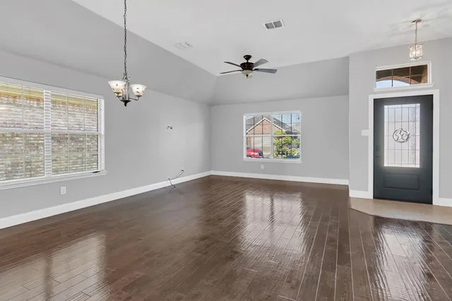 a view of an empty room with window and wooden floor