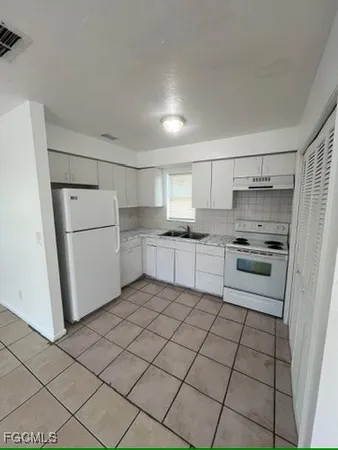 a kitchen with white cabinets and white appliances