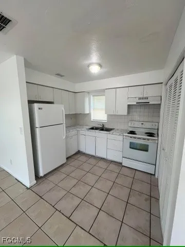 a kitchen with white cabinets and white appliances