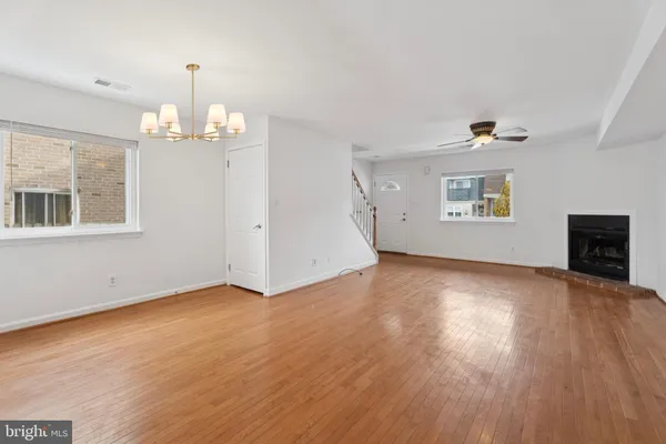 an empty room with wooden floor chandelier and windows