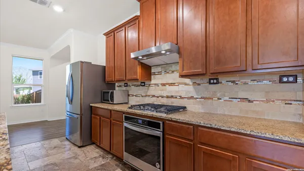 a kitchen with stainless steel appliances granite countertop a stove a refrigerator and a white cabinets