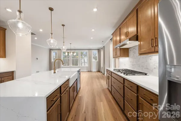 a kitchen with stainless steel appliances granite countertop a refrigerator a sink dishwasher a stove and a wooden floors