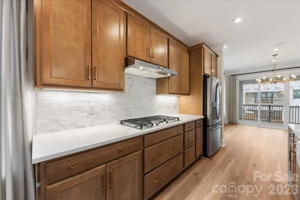 a large kitchen with stainless steel appliances kitchen island a large counter top a sink and a wooden floor