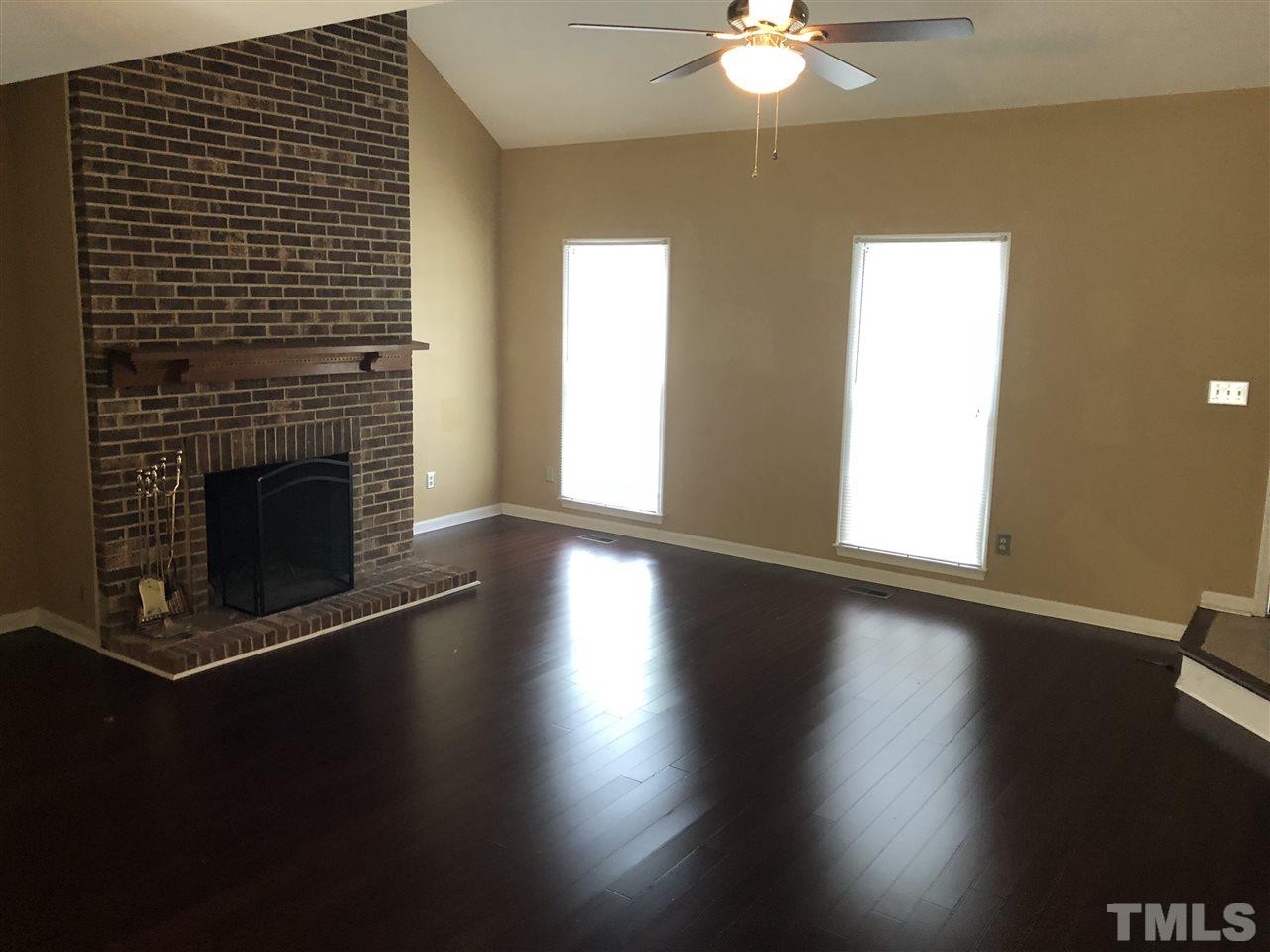 11812 North Exeter Way Raleigh, NC 27613 - Photo 4 of 25 a view of a livingroom with wooden floor a fireplace and a window