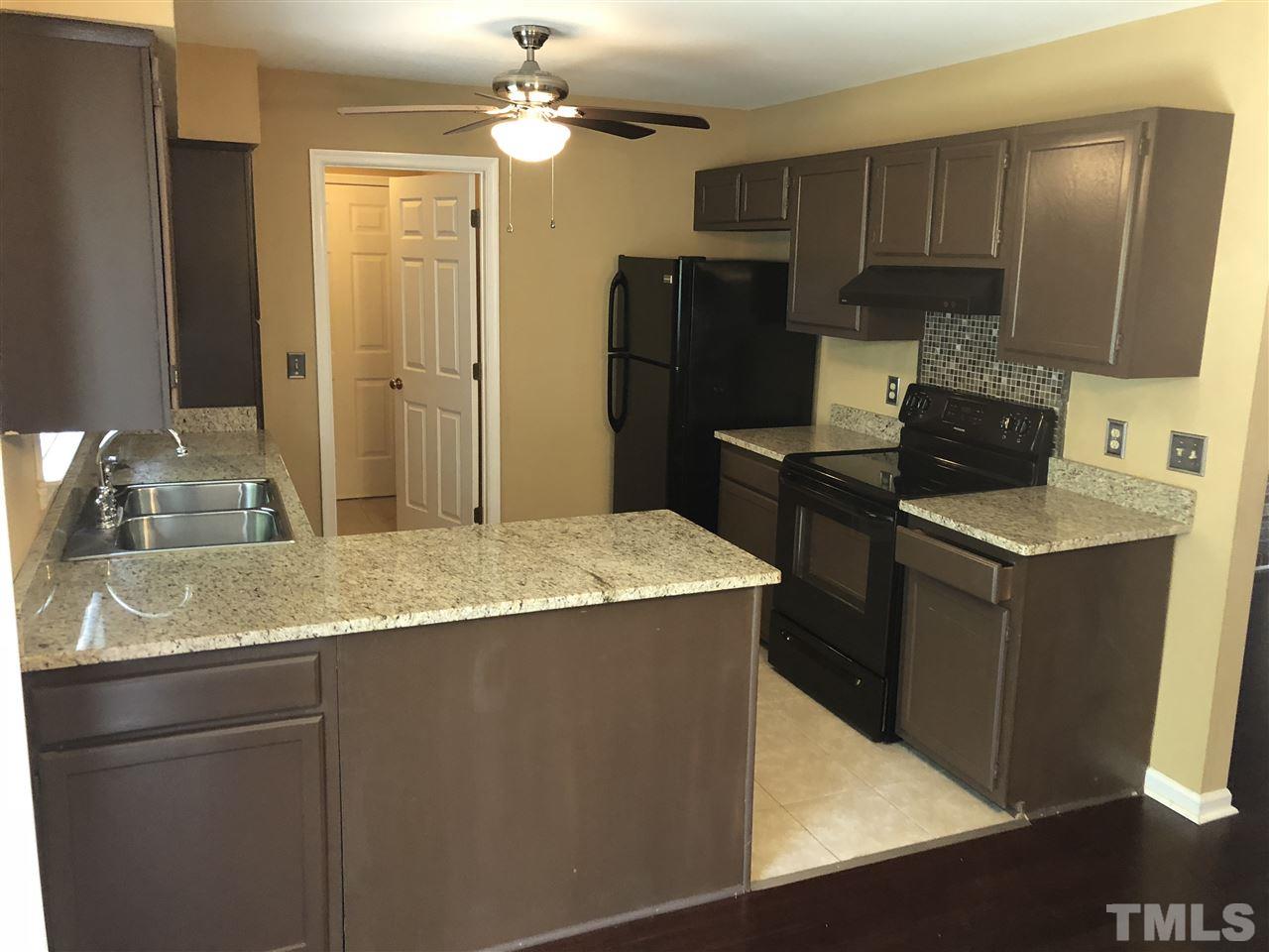 11812 North Exeter Way Raleigh, NC 27613 - Photo 8 of 25 a kitchen with kitchen island a counter top space appliances and a sink
