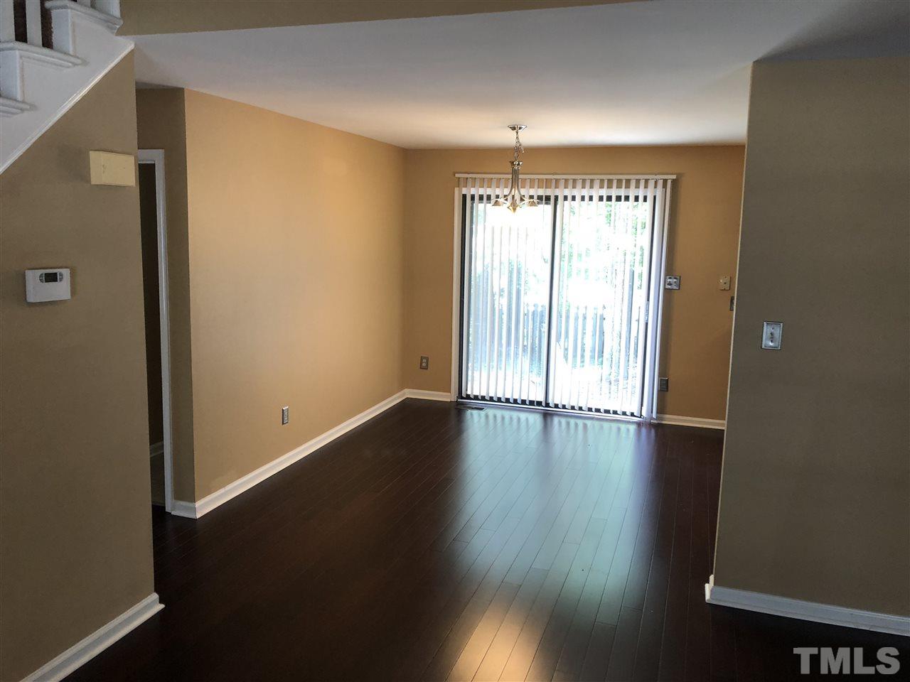 11812 North Exeter Way Raleigh, NC 27613 - Photo 10 of 25 an empty room with wooden floor and windows with curtains