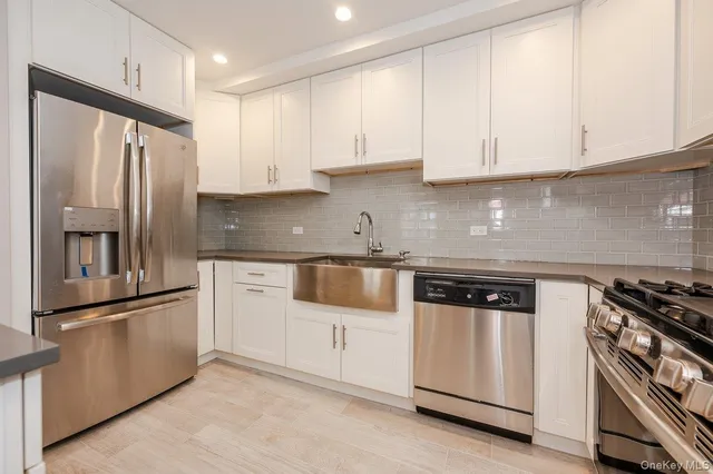 a kitchen with granite countertop white cabinets and stainless steel appliances