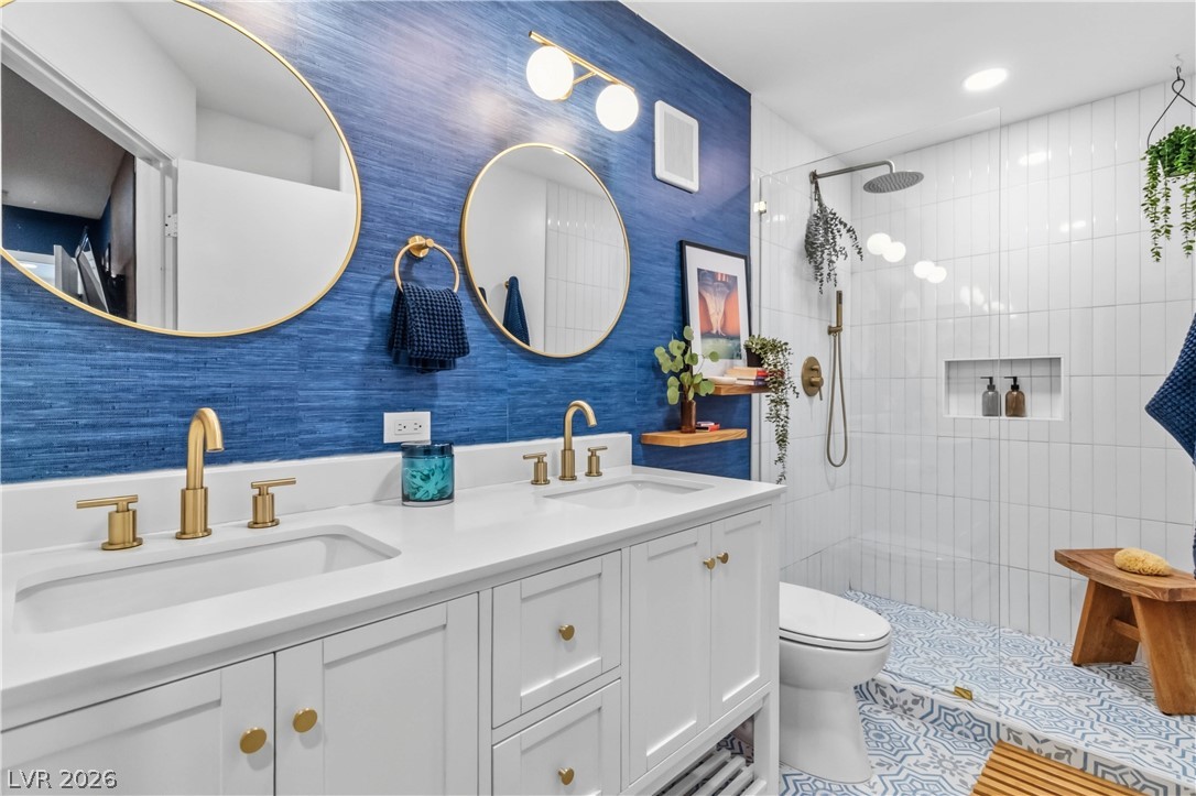 7950 West Flamingo Road, Unit 1180 Las Vegas, NV 89147 - Photo 18 of 26 A well-appointed bath features a double vanity with polished gold fixtures and a clear glass shower.