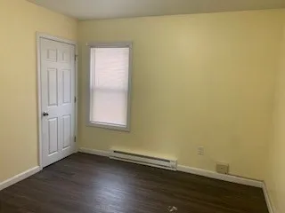 an empty room with wooden floor and a window
