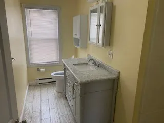 a bathroom with a granite countertop sink a toilet and a mirror