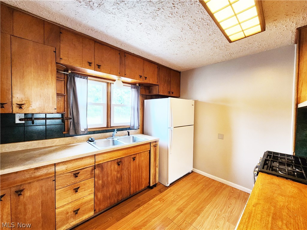 30 West Wilbeth Road, Unit A Akron, OH 44301 - Photo 6 of 16 Kitchen with range, light wood-type flooring, a textured ceiling, white refrigerator, and sink