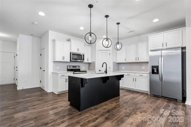 a kitchen with stainless steel appliances granite countertop a sink a stove a refrigerator and a wooden floor