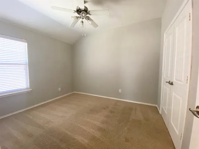 an empty room with windows and fan