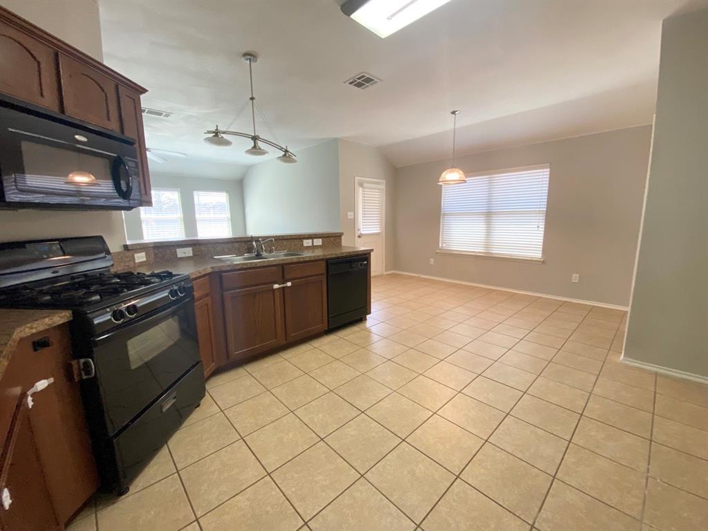 9717 Mystic Dunes Drive McKinney, TX 75072 - Photo 3 of 16 a kitchen with stainless steel appliances granite countertop a stove a sink and a microwave