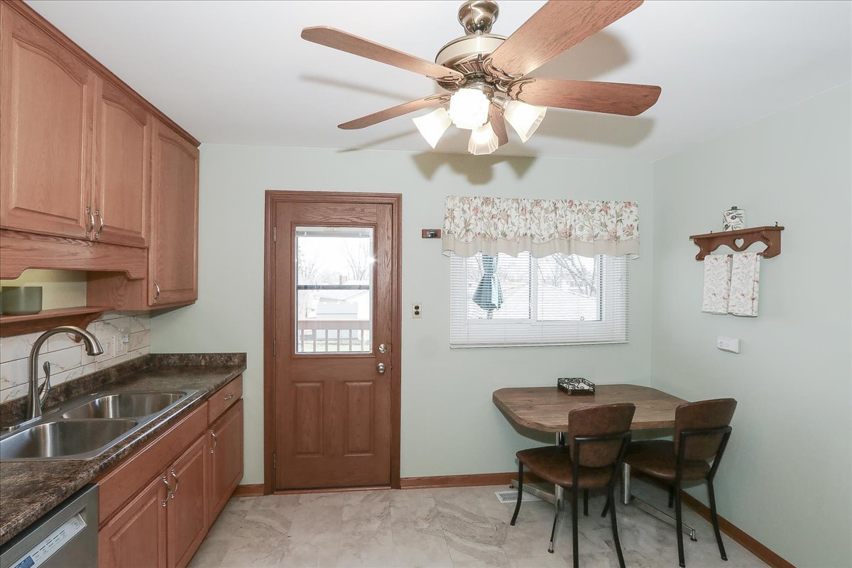 1335 Gentry Road Hoffman Estates, IL 60169 - Photo 14 of 33 a kitchen with stainless steel appliances granite countertop a sink a stove a dining table and chairs with wooden floor
