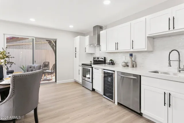 a kitchen with stainless steel appliances granite countertop a stove top oven a sink a dining table and chairs with wooden floor