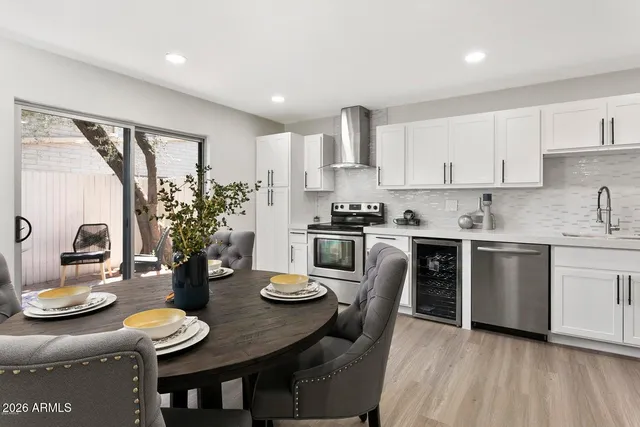 a kitchen with stainless steel appliances granite countertop a stove a sink a refrigerator and white cabinets with wooden floor