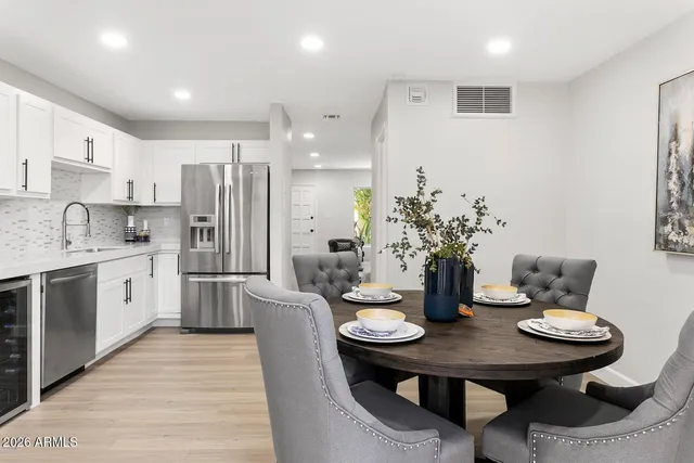 a kitchen with stainless steel appliances kitchen island granite countertop a dining table chairs and a refrigerator